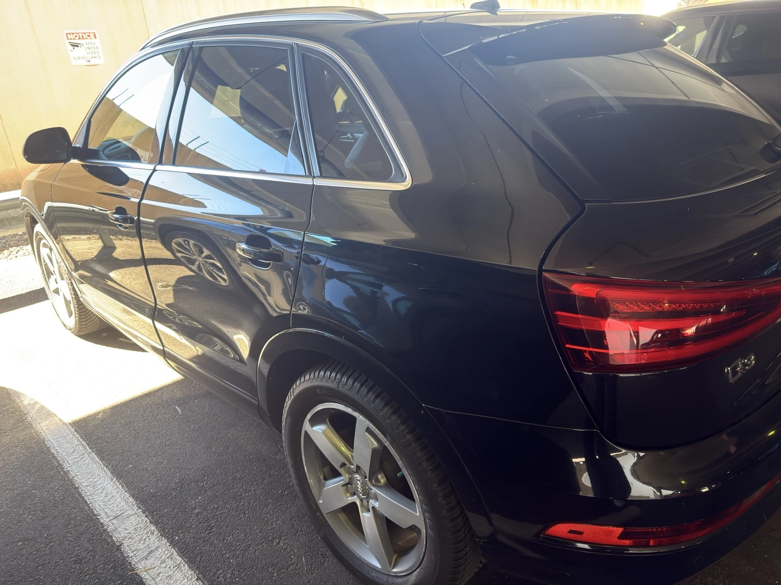 Owner's black 2015 Audi Q3 viewed from the rear three-quarter angle in a parking garage